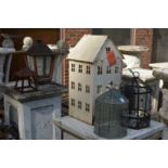 A terrarium, a metal house shaped candle holder and other similar items.