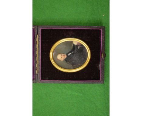 A portrait miniature of a Gentleman seated at a desk in a leather case.