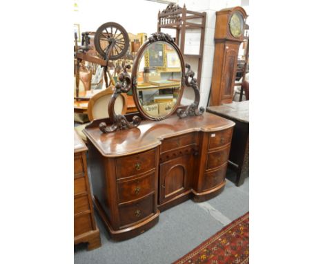A Victorian mahogany dressing chest with oval mirror and an arrangement of drawers and a cupboard door.