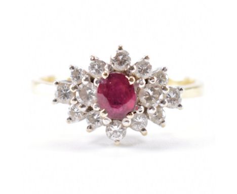 A hallmarked 18ct yellow gold, diamond &amp; ruby cluster ring. The ring having a central oval cut ruby surrounded by a halo 