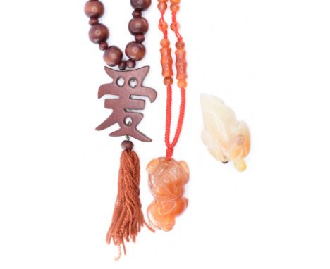 Two Chinese necklaces and a pendant. A wooden bead necklace with carved Chinese symbol measures 84cms, pendant 12cms includin