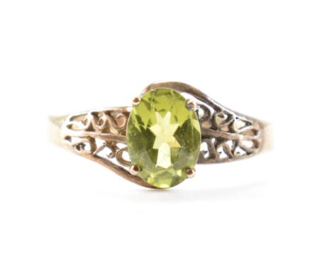 A hallmarked 9ct gold &amp; peridot solitaire ring. The ring having an oval cut peridot in prong setting to pierced scrolling