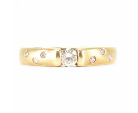 An 18ct yellow gold &amp; diamond ring. The ring of brushed yellow gold having a central round cut channel set diamond flanke