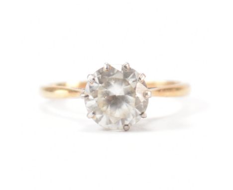 A vintage gold and white stone single stone ring. The ring being set with a round brilliant cut white stone in a cathedra set