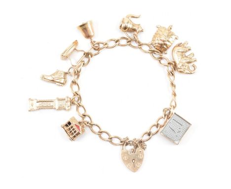 A hallmarked 9ct yellow gold heart padlock charm bracelet &amp; charms. The chain bracelet comprised of curb links united by 