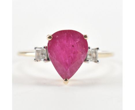 A hallmarked 9ct gold ruby and diamond ring. The ring being set with a pear cut ruby flanked by two square cut diamonds. Hall