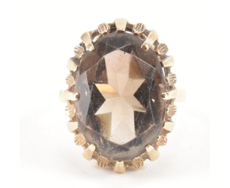 A hallmarked 9ct gold and smoky quartz dress ring. The ring being set with an oval cut smoky quartz stone within a pierced se