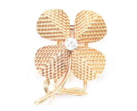 A vintage mid 20th Century Sterle Paris 18ct gold and diamond flower lapel pin. The pin having textured leaves with a round b