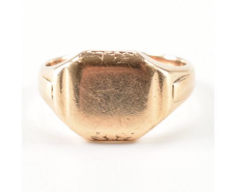 A hallmarked 9ct yellow gold signet ring. The ring having a squared head with decorative shoulders to a tapered shank. Hallma