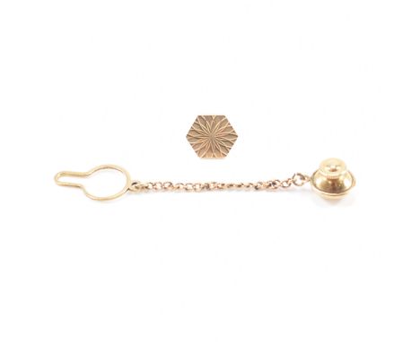 A hallmarked 9ct yellow gold engine turned tie pin. The pin having a hexagonal head with petal like engine turned design to s