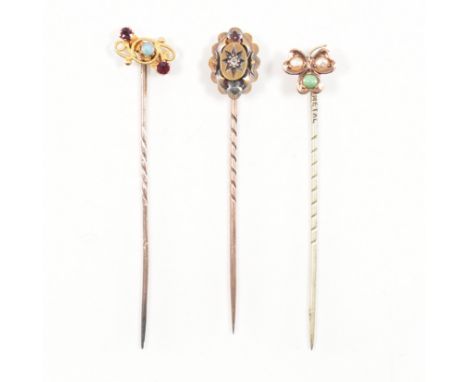 A collection of three gold &amp; gem set antique stick pins. The first pin having a central round cut diamond in star setting