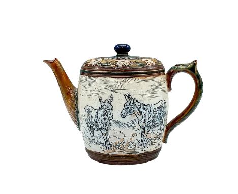 A covered teapot featuring incised donkeys to sides, and white flowers on the top. Doulton Lambeth impressed stamp. Hannah Ba