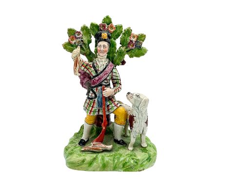 A hand painted pearlware bocage figure of a man holding a bird and rifle. A hunting hound beside him. Dimensions: 5.25"L x 4W