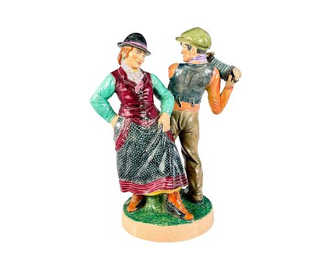 Glazed earthenware figure modeled as a dancing man and woman, holding an accordion up to his right shoulder in beautiful colo