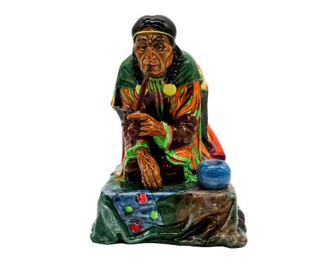 Figure of a Native American Indian in traditional attire smoking a tobacco pipe. Brown and green coloration.Royal Doulton bac