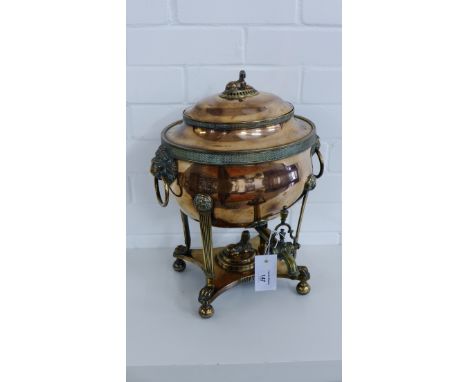 An Egyptian Revival copper and brass hot water urn, the lid with Sphinx finial, the oval pot with lion masks handles to sides