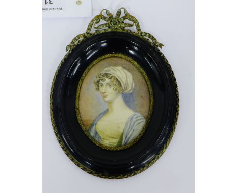 Oval painted portrait miniature on ivorine panel of a young woman dressed in white and blue dress with her curled hair in a s