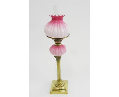 A VICTORIAN BRASS CORINTHIAN COLUMN OIL LAMP WITH PINK SHADED GLASS FOUNT, BRASS BURNER AND MATCHING GLASS SHADE, 54CM H EXCL
