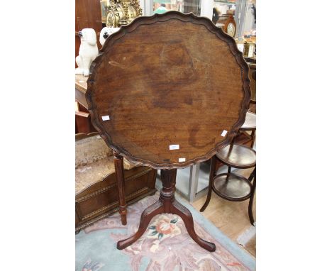 A George III style mahogany tripod table, the shaped top with a pie crust edge, raised on a baluster turned column, standing 