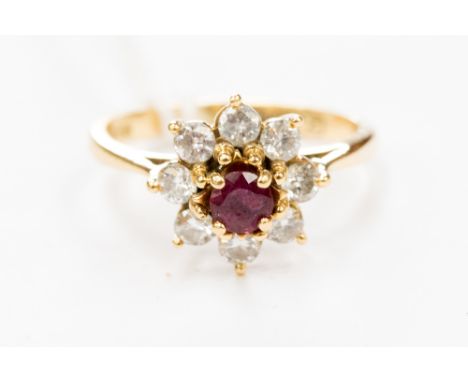 A ruby and diamond flower shape cluster ring, the central ruby measuring approx. 3.5 x 3.5 mm, the eight diamond surround tot
