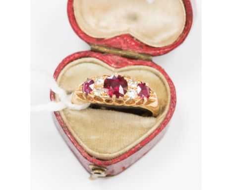 A ruby and diamond, seven stone boat head ring, the centre ruby approx 5.5 mm diameter, the shank stamped '18', approx gross 