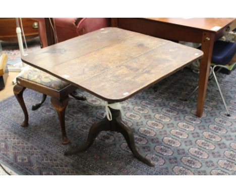 A George III oak tilt-top tripod table, circa 1770 the square top raised on a baluster and ring turned column, standing on ca