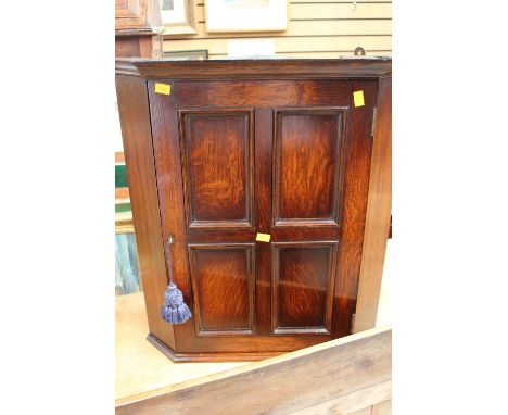 A 20th Century oak wall hanging cupboard, the single four panel door opening to reveal a single fitted shelf