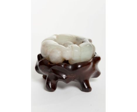 A LATE NINETEENTH CENTURY CHINESE CARVED AND PIERCED JADE FIGURE, modelled with three boys forming a circle, on hardwood stan