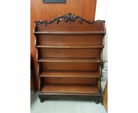 A GOOD VICTORIAN MAHOGANY FIVE-SHELF WATERFALL BOOKCASE, with cartouche crest issuing leaf scrolls, over graduating shelves a