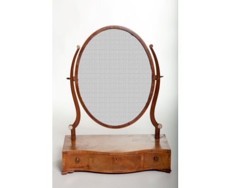 A GEORGE III PERIOD MAHOGANY SWING-FRAME DRESSING TABLE MIRROR, with serpentine shaped front and oval plate, raised on shaped