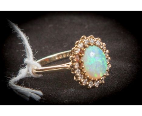 AN OVAL OPENED OPAL AND DIAMOND SET CLUSTER RING, with cabochon opal, surrounded b a band of diamonds, set in 18K yellow gold