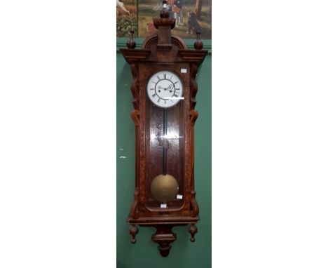 A VICTORIAN FIGURED WALNUT VIENNA STYLE WALL CLOCK, with arched pediment and three urn finials, above a two-stage enamel dial