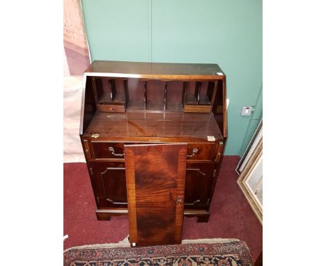A GEORGIAN STYLE MAHOGANY SLOPE-FRONT BUREAU, the interior fitted with drawers and pigeon holes, with two doors below, raised