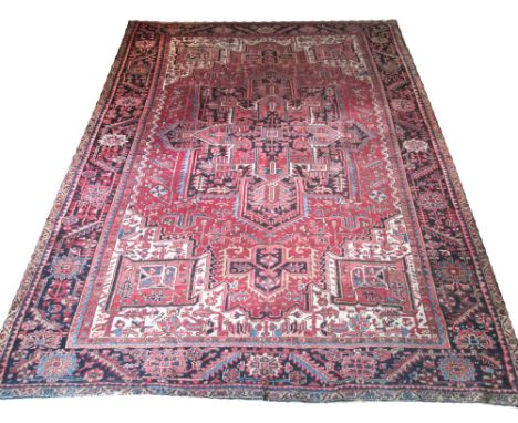 ANTIQUE PERSIAN HERIZ CARPET, 375cm x 257cm, central medallion on a terracotta field of stylised palmettes and vines within c