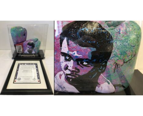 A cased pair of Muhammad Ali signed boxing gloves, also painted with portrait of Ali by Bill Lopa. With framed COA. 