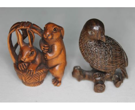 Two oriental carved wooden netsuke, one formed as a bird on branch and the other a pair of rabbits with a basket.  
