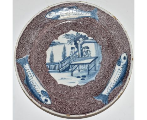 English Delft plate, London c1750, decorated with a chinoiserie garden scene of two figures at a table, within a border of th