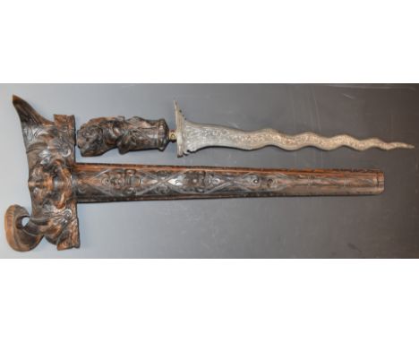 An eastern Kris dagger with 38cm blade, heavily carved handle and scabbard and glass inset gilt collar, overall&nbsp;length 5