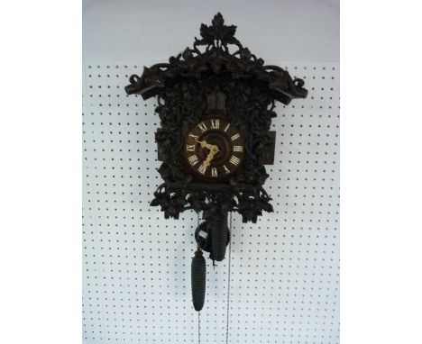 A Black Forest Cuckoo Clock, with carved bone hands, two weight movement and leaf carved case, with retailer's label on back 