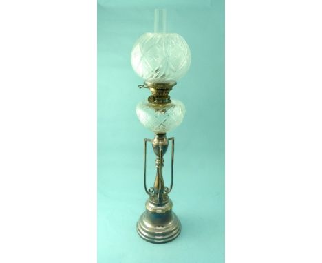 An Edwardian silver plated Oil Lamp, with ornate scrolled column, supporting corresponding cut glass reservoir and globe, 32½