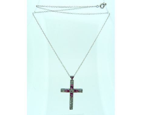 A diamond and ruby set Crucifix, mounted in white metal, with ruby set suspension link, and on a silver chain, 1½in (4cm) x 1