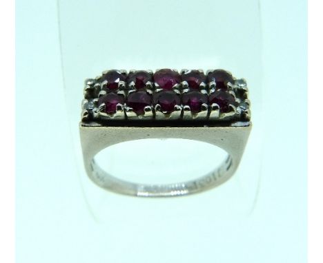A modern Ring, with two rows of six circular cut rubies, with a small diamond point at each shoulder, mounted in white metal,