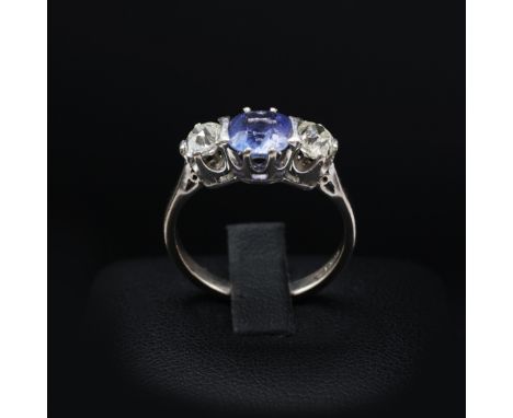 AN 18CT WHITE GOLD CEYLON SAPPHIRE AND DIAMOND TRILOGY RING, the central mixed cut sapphire of approximately 1.00 carat, flan