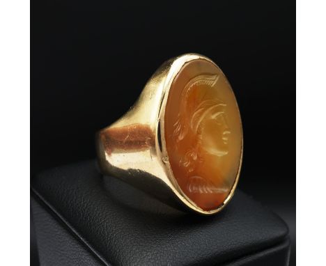 A 9CT GOLD SIGNET RING, set with a carnelian intaglio depicting the profile of a warrior, open backed setting, the shank hall