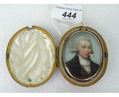 An early 19th century portrait miniature of a gentleman, painted on ivory, in frock coat and ruffed cravat, glazed hair panel