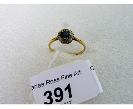 A sapphire and diamond cluster ring, the cushion cut sapphire within a border of mixed old cut diamonds.