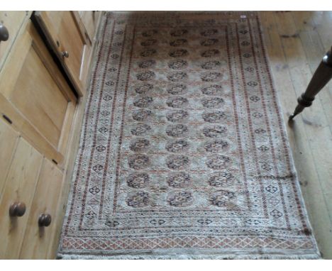 A rectangular Eastern-style carpet, having stylized foliate design on a mushroom ground (177cm x 119cm).