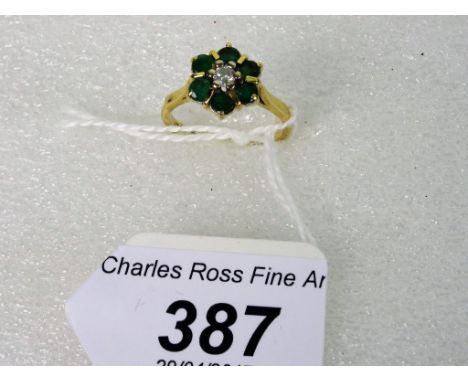 An emerald and diamond cluster ring, with central brilliant cut diamond and a six stone circular cut emerald surround.