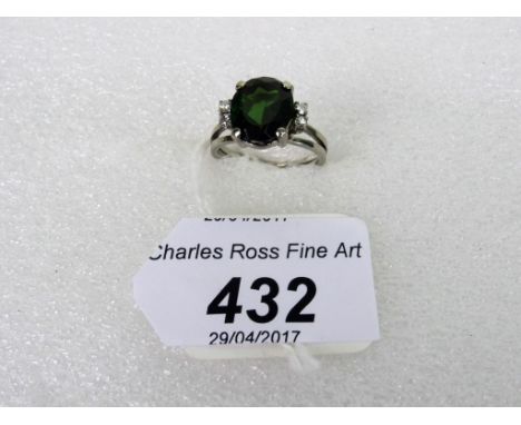 A tourmaline and diamond ring, the oval cut dark green tourmaline in simple claw mount, with two stone brilliant cut diamond 