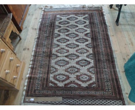 An Eastern-style carpet, having repeating geometric shapes to the central field (191cm x 124cm).